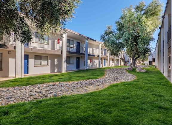 A row of apartment buildings with a grassy area in front.