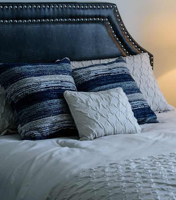 A bedroom with a large bed and two blue lamps.