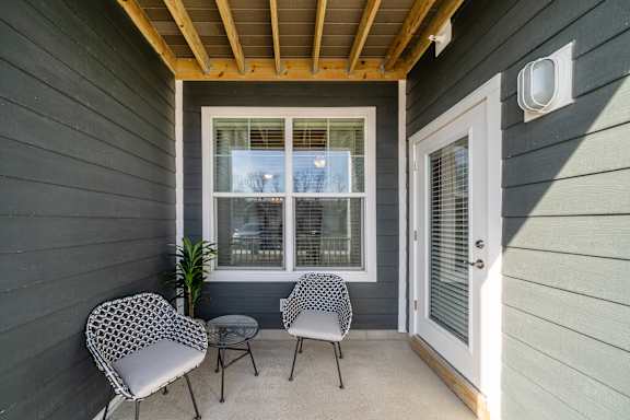a covered porch with two chairs and a table