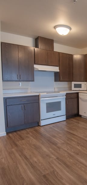 an empty kitchen with white appliances and dark wood cabinets