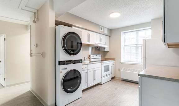 A white kitchen with a washer and dryer built in.