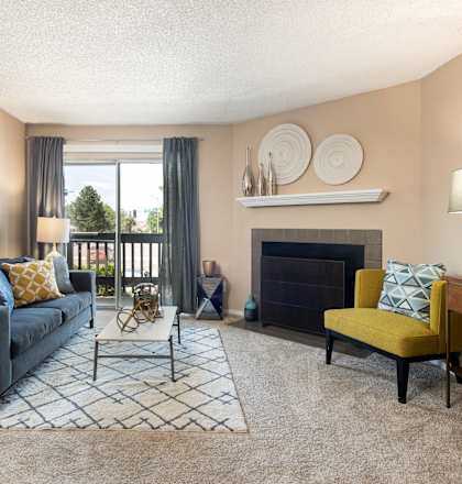 A living room with a black couch, a yellow chair, and a fireplace.