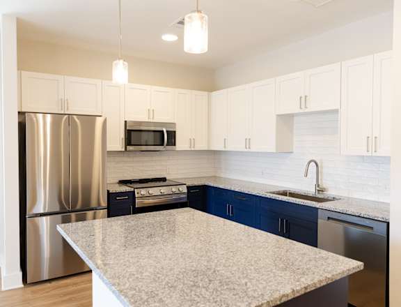 A kitchen with a granite countertop and stainless steel appliances.