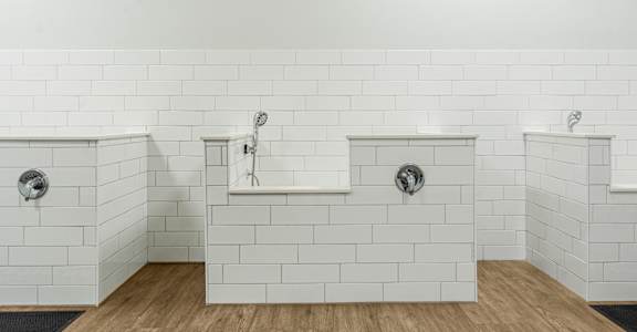A white tiled bathroom with two sinks and a bathtub.
