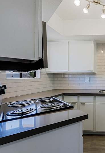 A modern kitchen with white cabinets and a black countertop.