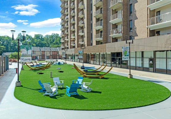 a grassy area with lounge chairs and hammocks in front of an apartment building