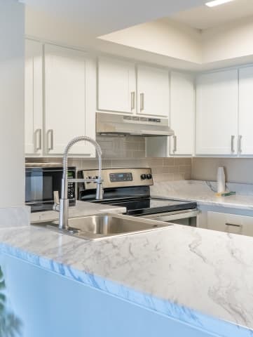 a kitchen with white cabinets and a white marble counter top