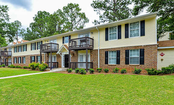 exterior view of apartments with a green lawn and trees