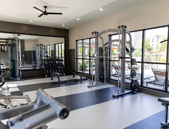 A gym with a variety of equipment including a weight bench, a leg press machine, and a cable machine.