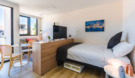 a bedroom with a bed and a desk and a living room