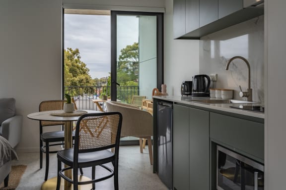 a kitchen and living room with a table and chairs and a balcony