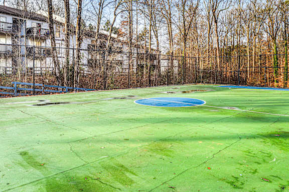 A green tennis court with a blue pool in the middle.