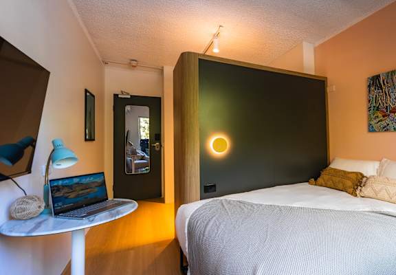 a bedroom with a bed and a laptop on a desk
