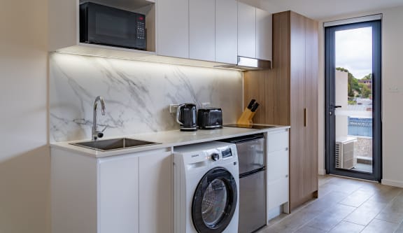 a washer and dryer in a kitchen with a sink and a window