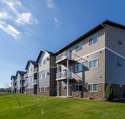 A large apartment building with a grassy area in front.