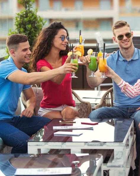 Four people toasting with drinks on a table.