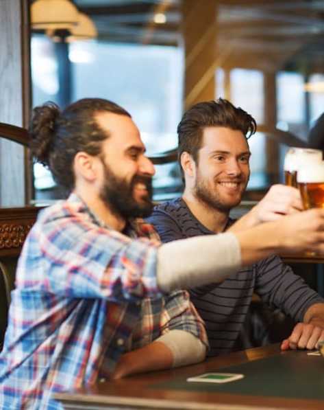 Two men toasting with beer glasses in a bar.