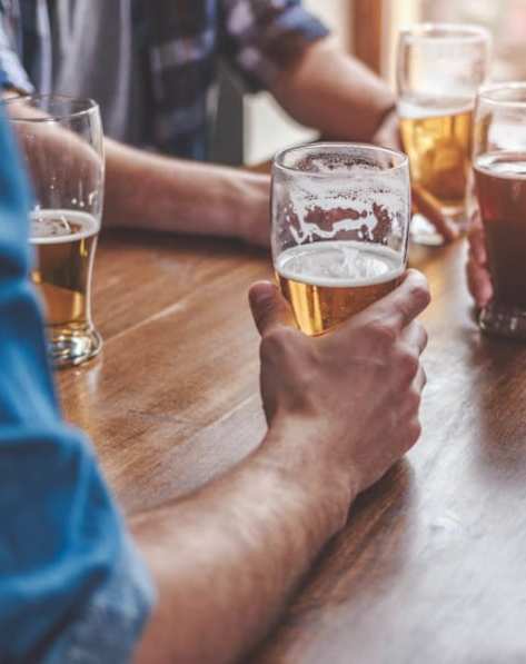 A person is holding a glass of beer in a bar.