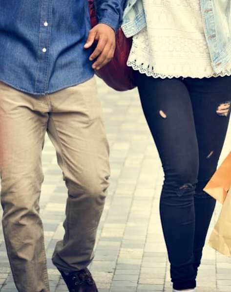 A man and a woman walking together while carrying shopping bags.