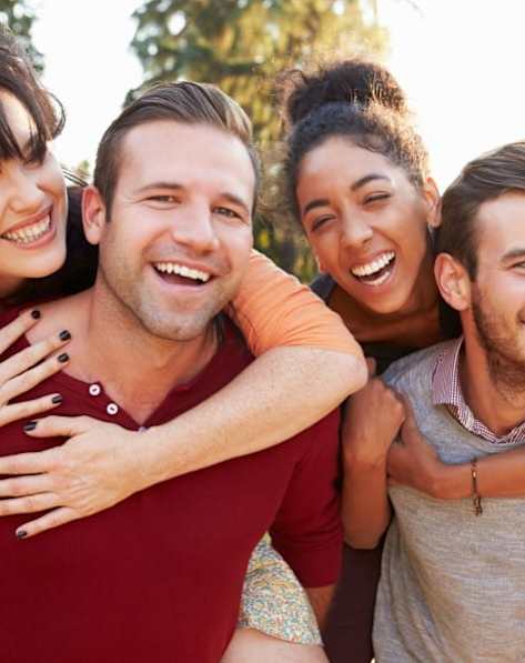 Four people hugging each other in a sunny outdoor setting.