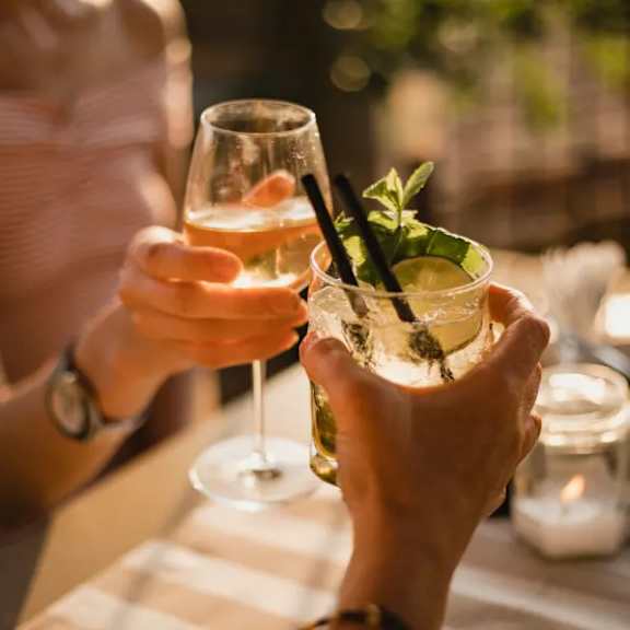 Two people toasting with drinks in their hands.