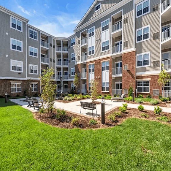 Apartment complex with a green lawn and trees in the courtyard.