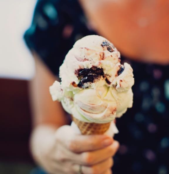 a person holding a cone with ice cream