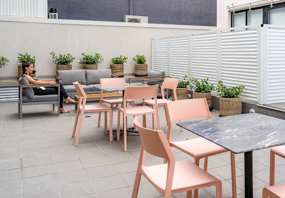 a patio with tables and chairs and a woman sitting on a couch