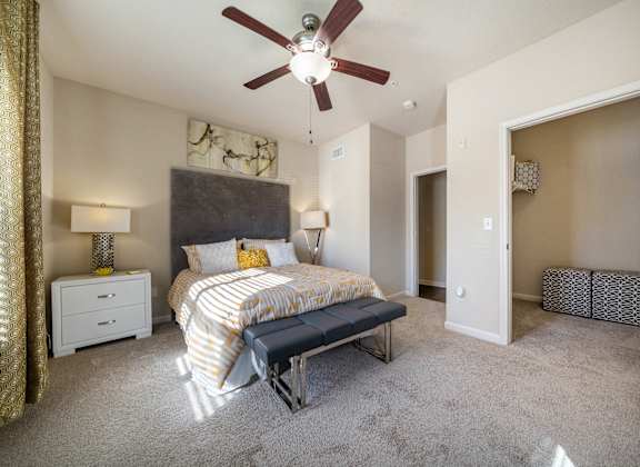 A bedroom with a bed, nightstand, and a ceiling fan.