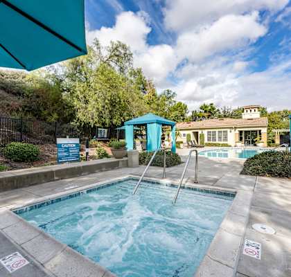 a swimming pool with two blue umbrellas and a house in the background at Alta Vista, Escondido, CA, 92026