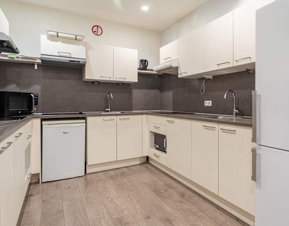 A kitchen with white cabinets and a white fridge.