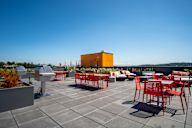 A patio with red chairs and a yellow building in the background.
