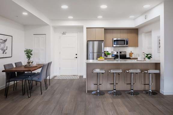 A modern kitchen with a dining table and bar stools.