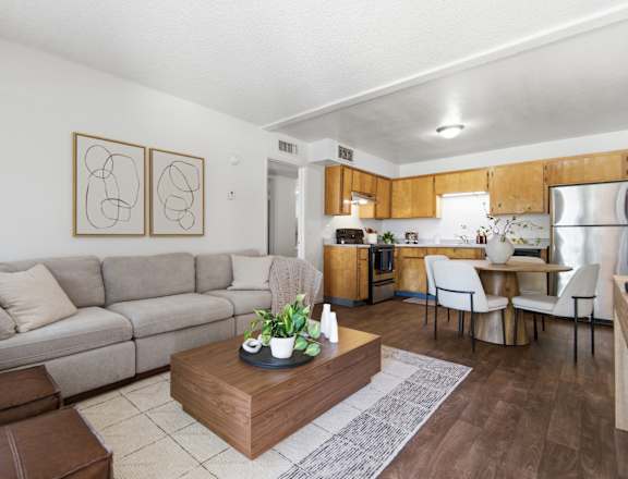A modern living room with a grey sofa, a coffee table, and a kitchen area in the background.