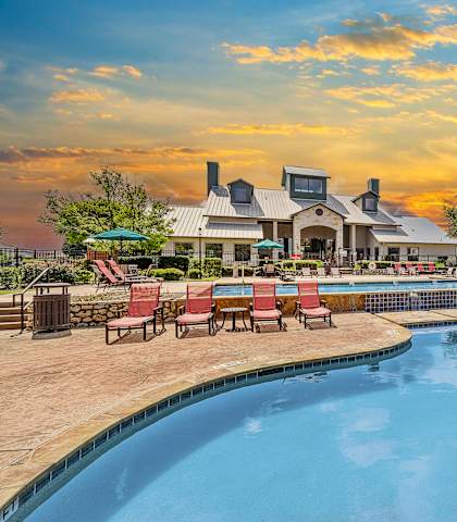 A large swimming pool with red chairs around it.