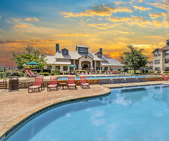 A large swimming pool with red chairs around it.