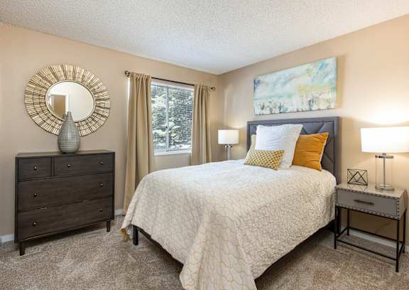 A bedroom with a bed, nightstand, and dresser.