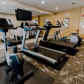 a gym with treadmills and weights and a tv