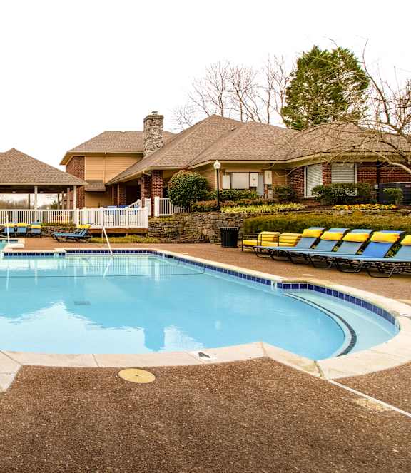 A large outdoor swimming pool with a hot tub and a house in the background.
