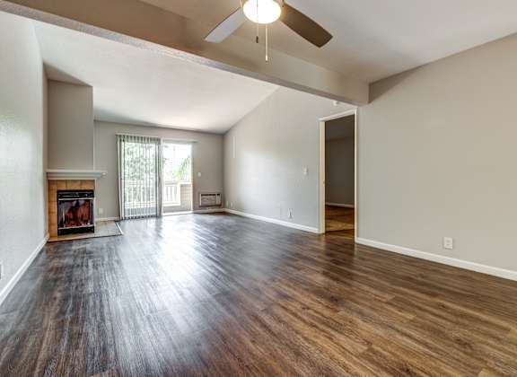an empty living room with a fireplace and a ceiling fan