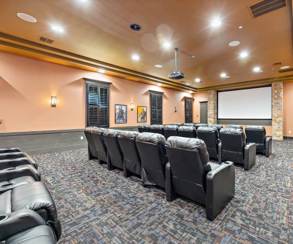 a large room with a projector screen and leather chairs