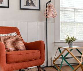 A living room with two chairs, one of which is red, and a small table with a plant on it.