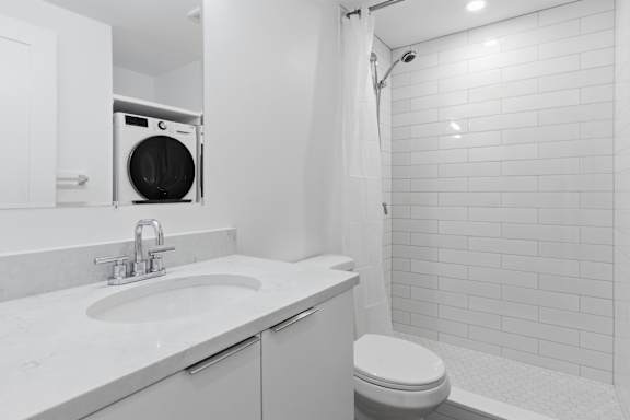 A white bathroom with a toilet, sink, and shower.