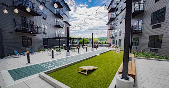 A patio area with a green lawn and a wooden bench.