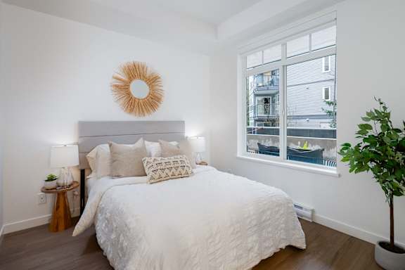 A bedroom with a large bed and a window overlooking a balcony.