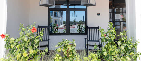 A patio with a black chair and a hanging light fixture.