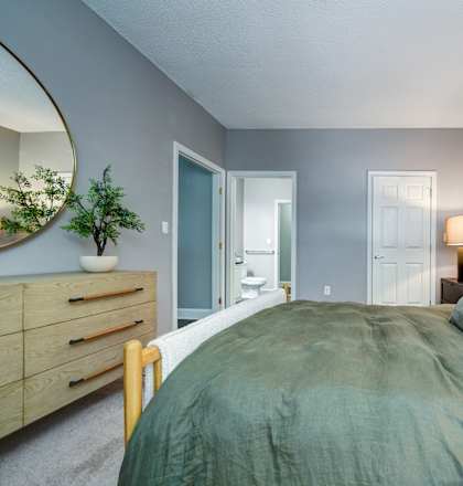 A bedroom with a bed, dresser, and mirror.