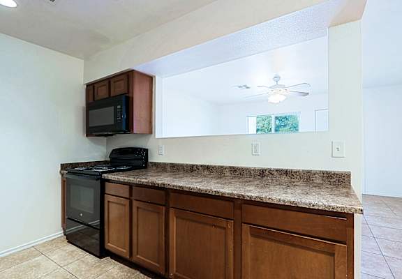A kitchen with brown cabinets and a granite countertop.