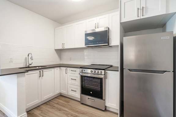 A kitchen with a stainless steel refrigerator and a microwave above the oven. at 608 Church Apartments, Toronto, ON, M4Y 2E7