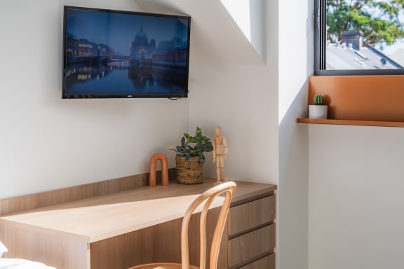 a bedroom with a desk and a tv on the wall